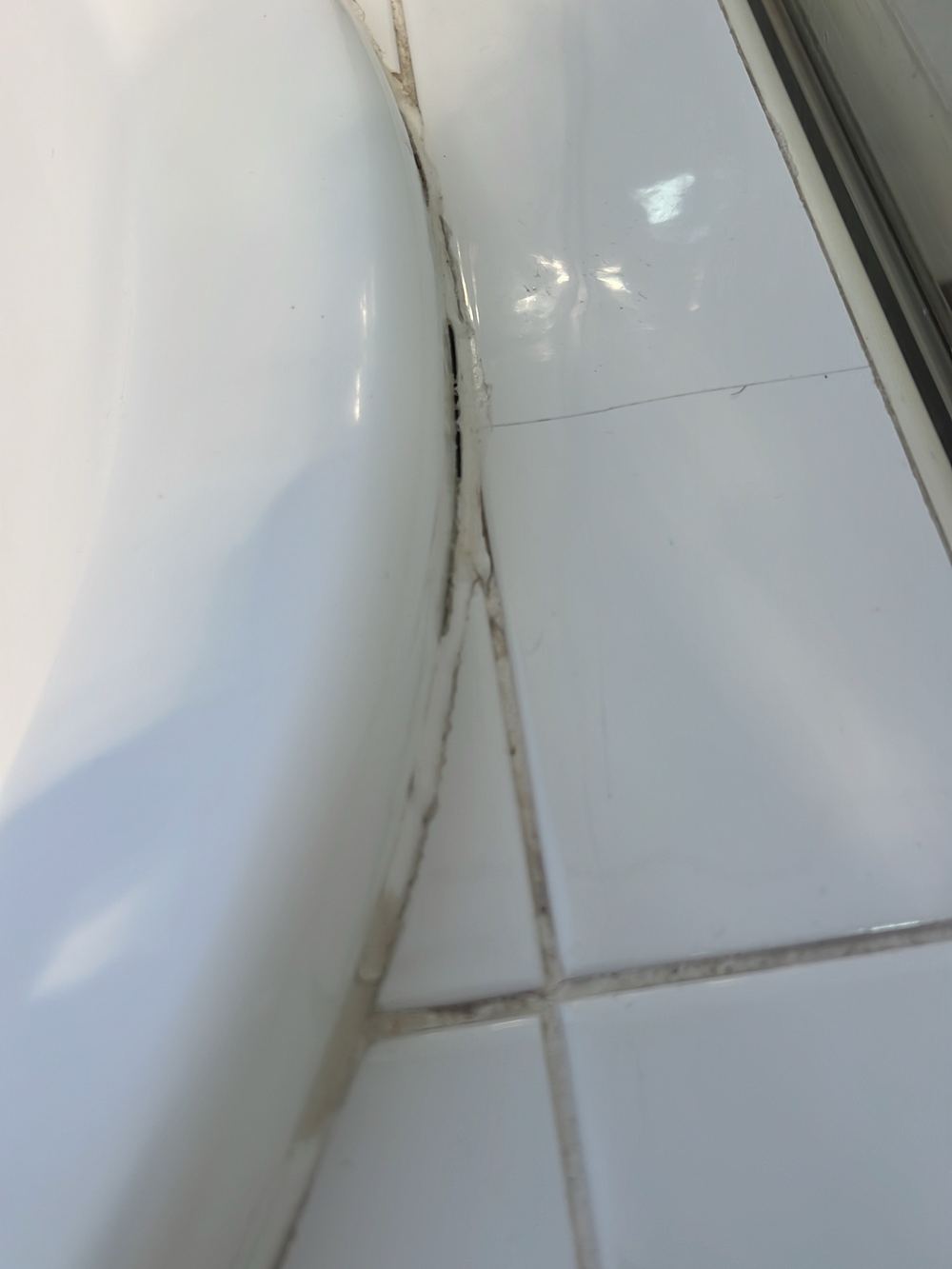 Old sealant discoloured with mould growth, due for replacement, found during a building and pest inspection in Stanhope Gardens